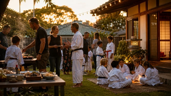 Families sharing a barbecue after grading at dusk, with children in gis playing together.